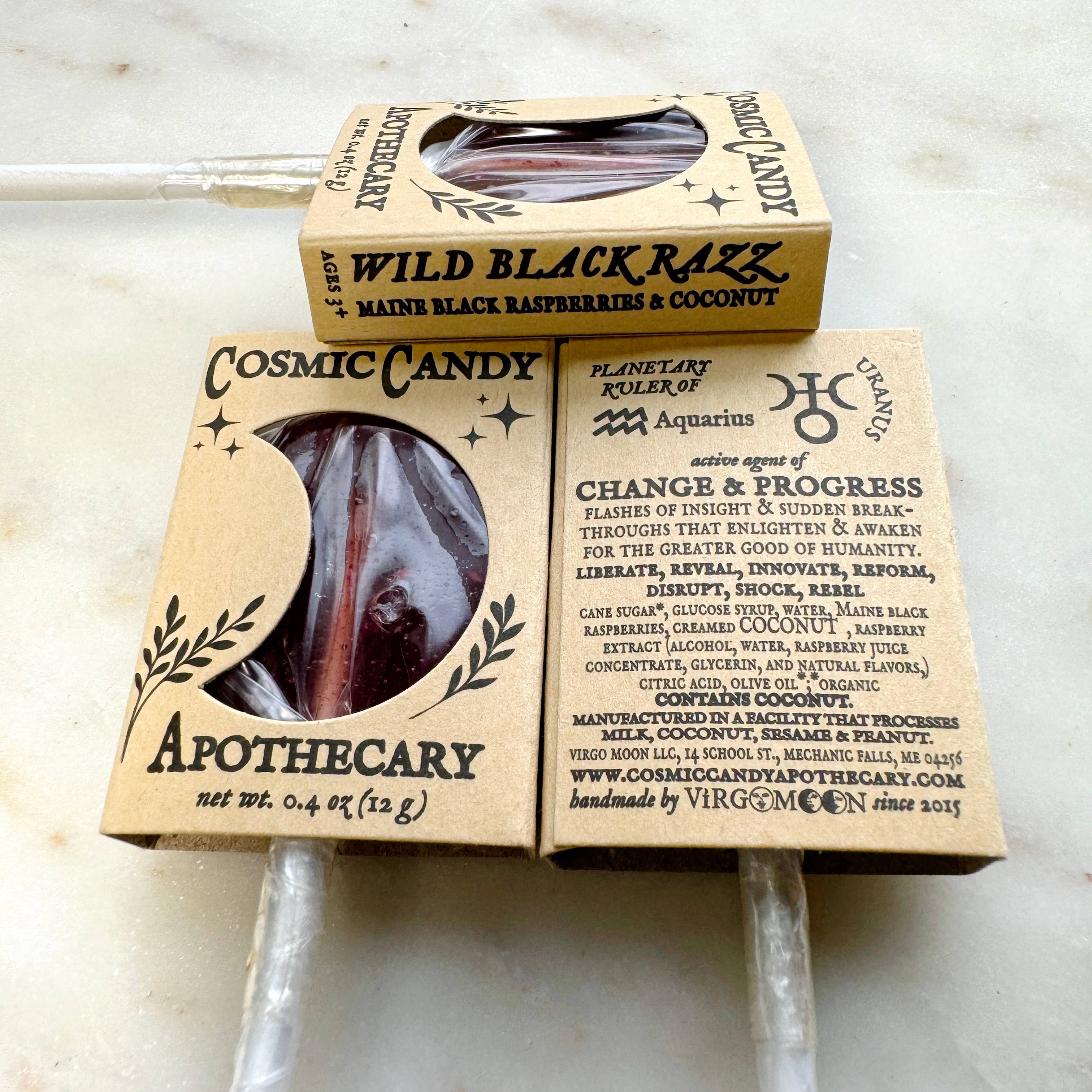 Two Cosmic Candy Apothecary lollipops in cardboard packaging on a marble surface.