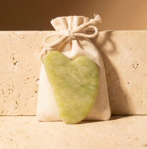 Heart-shaped green stone in front of a beige drawstring bag on a beige background 