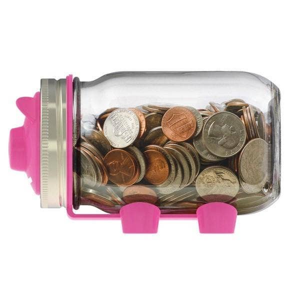 Glass jar with pink lid and base filled with coins on a white background